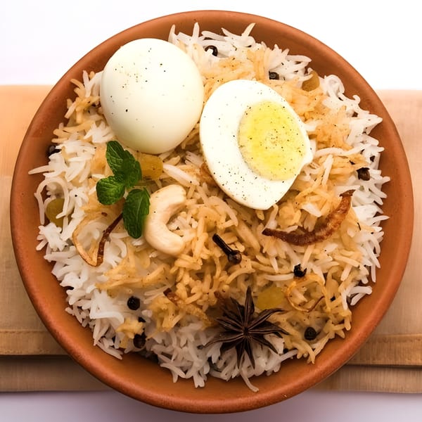 Egg Biryani with whole and halved boiled eggs, cashews, mint, and spices in a clay bowl.